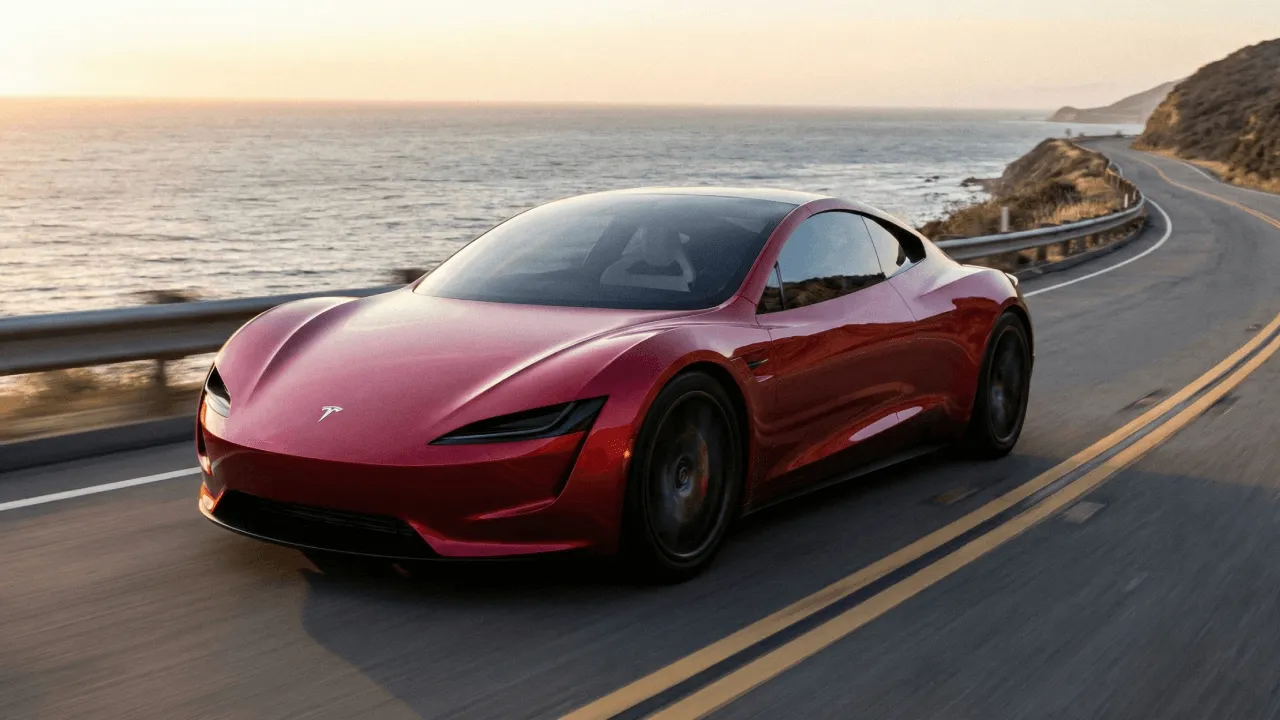 Red sports car driving along coastal highway